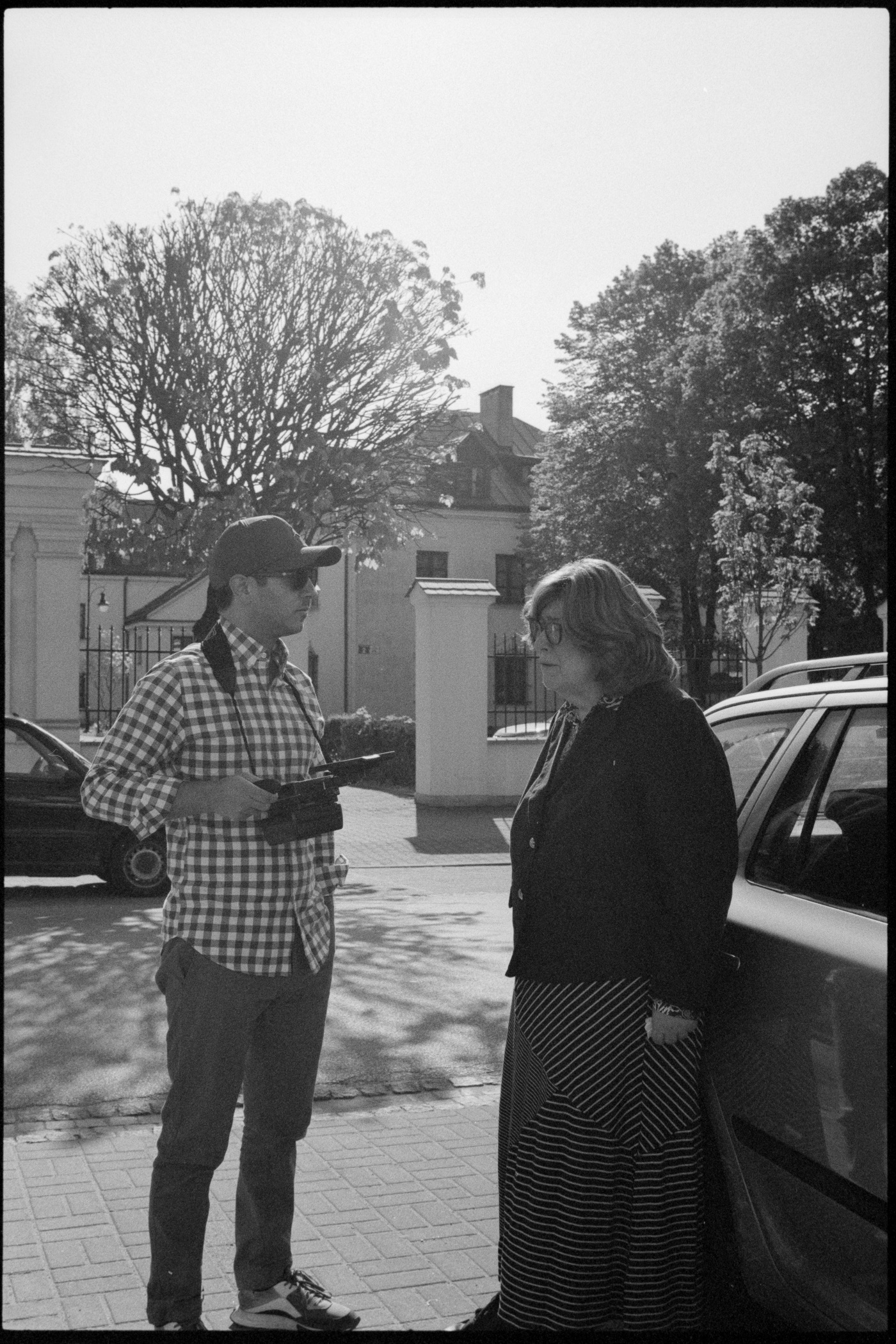 A camera operator films Ruth beside the cars on location.