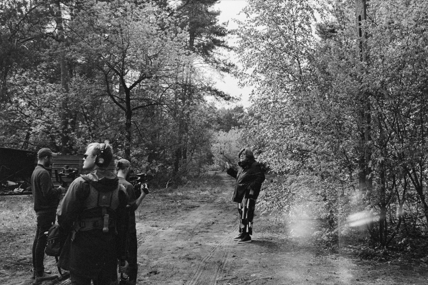 Camera and sound crew film Ruth as she gestures on a forest road.